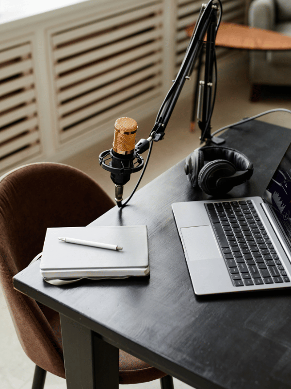 Desk with laptop, notebook, and microphone.